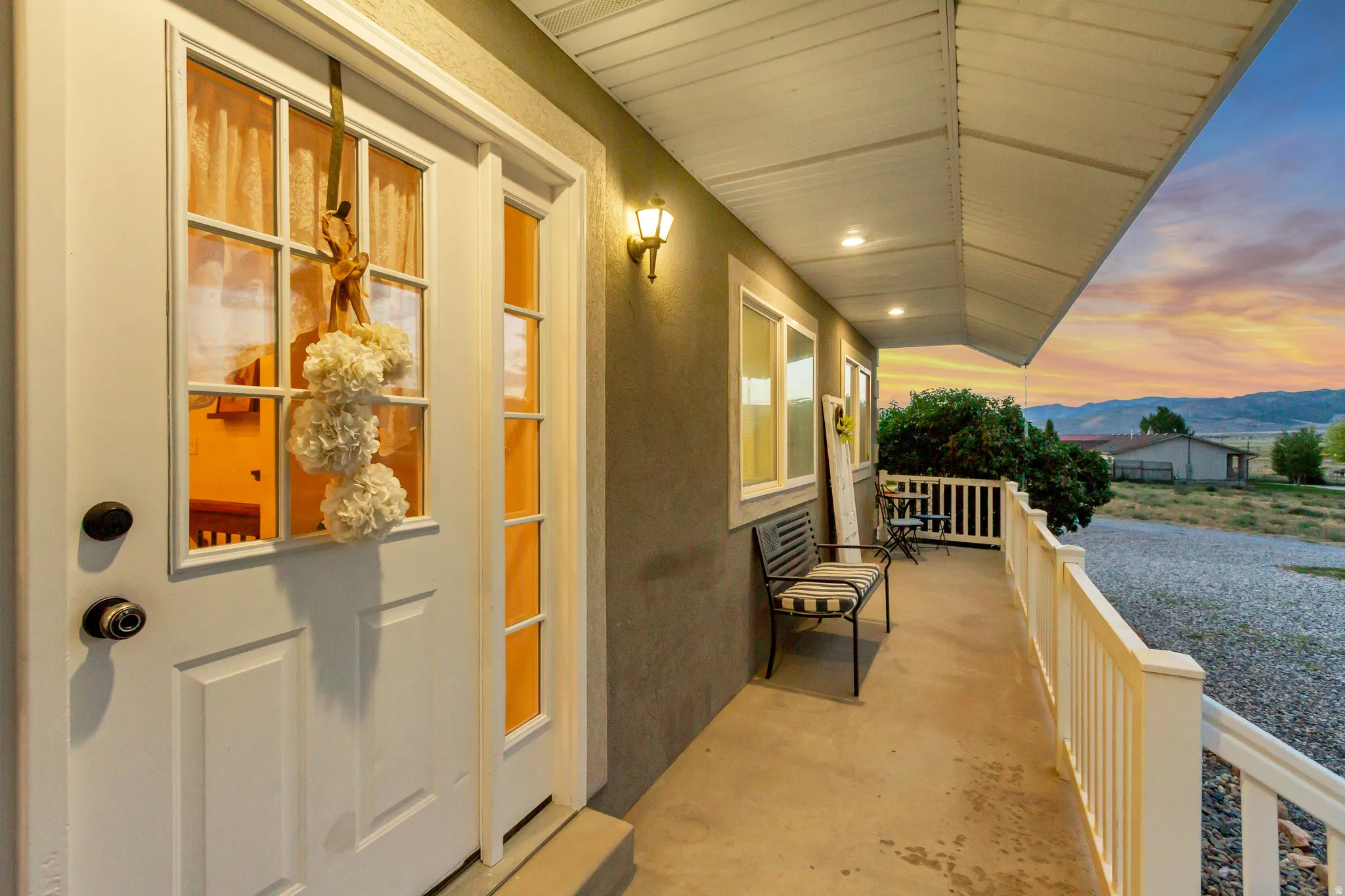 Covered front porch featuring a white entry door with glass panels, recessed lighting, and a protective railing