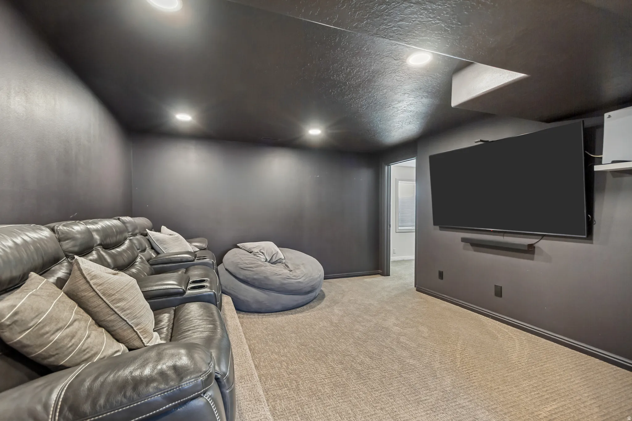 Dedicated media room featuring recessed lighting, dark painted walls, and light-toned carpeting