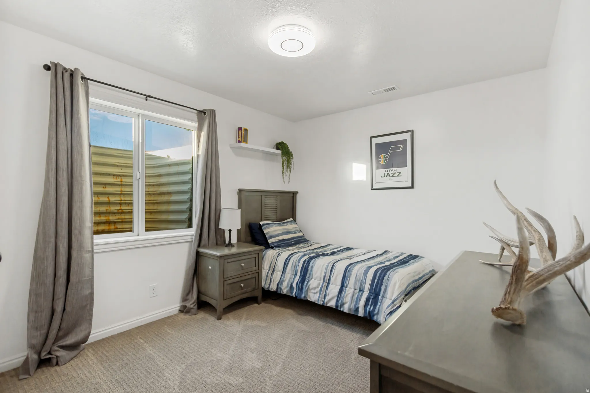 Carpeted room featuring a white window frame, neutral wall paint, and a built-in shelf