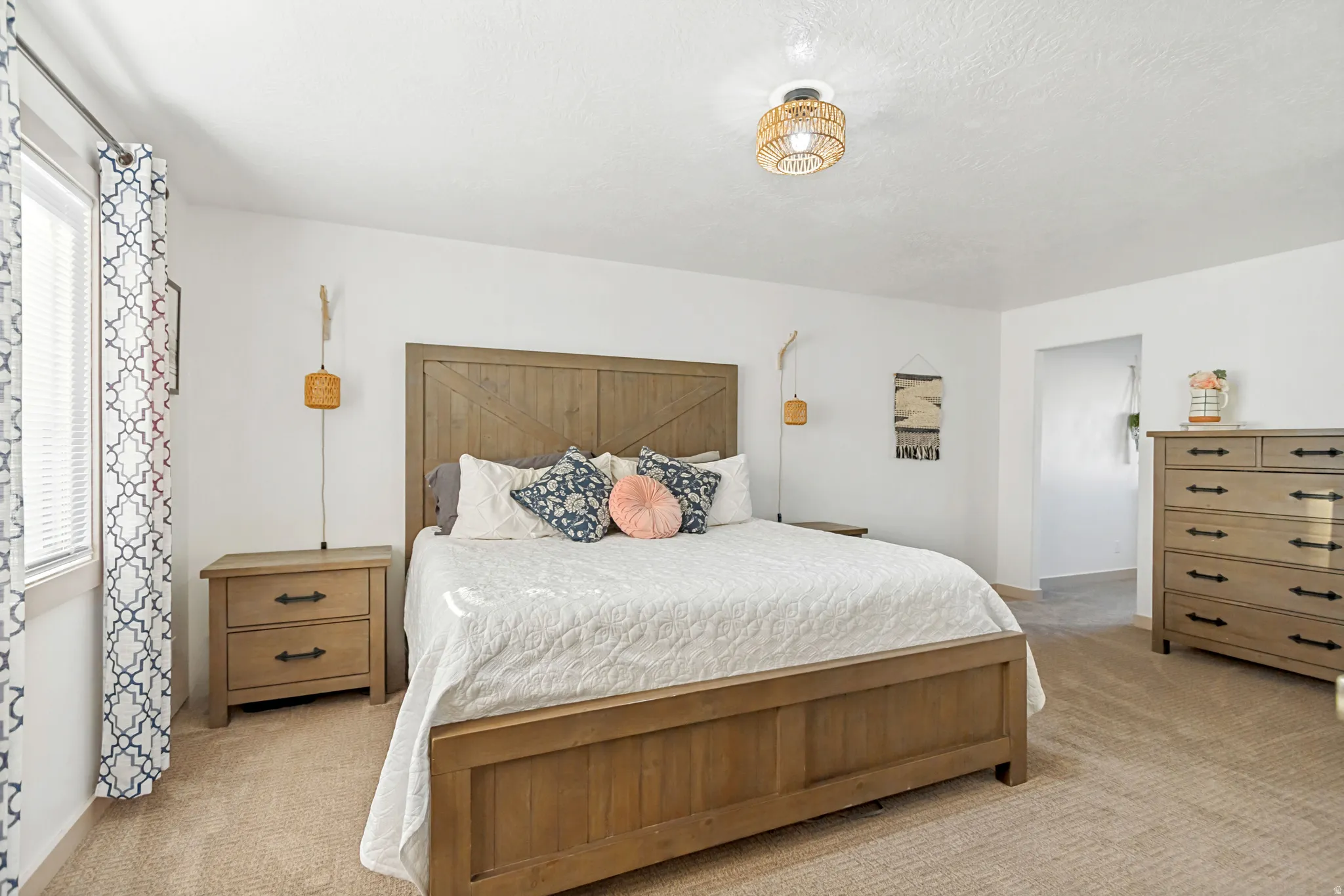 Bright interior space featuring a window with blinds, a woven light fixture, and textured ceiling