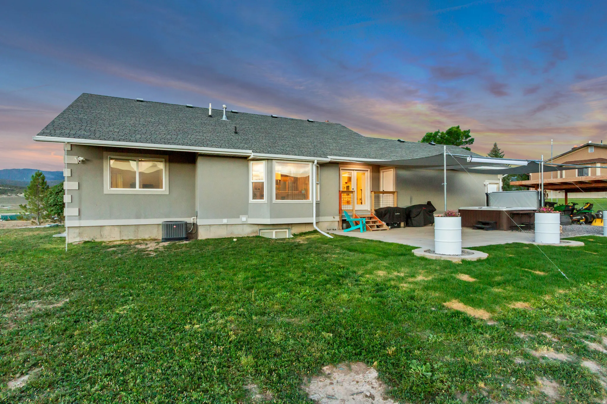 Expansive backyard featuring a concrete patio, hot tub, and a pergola structure