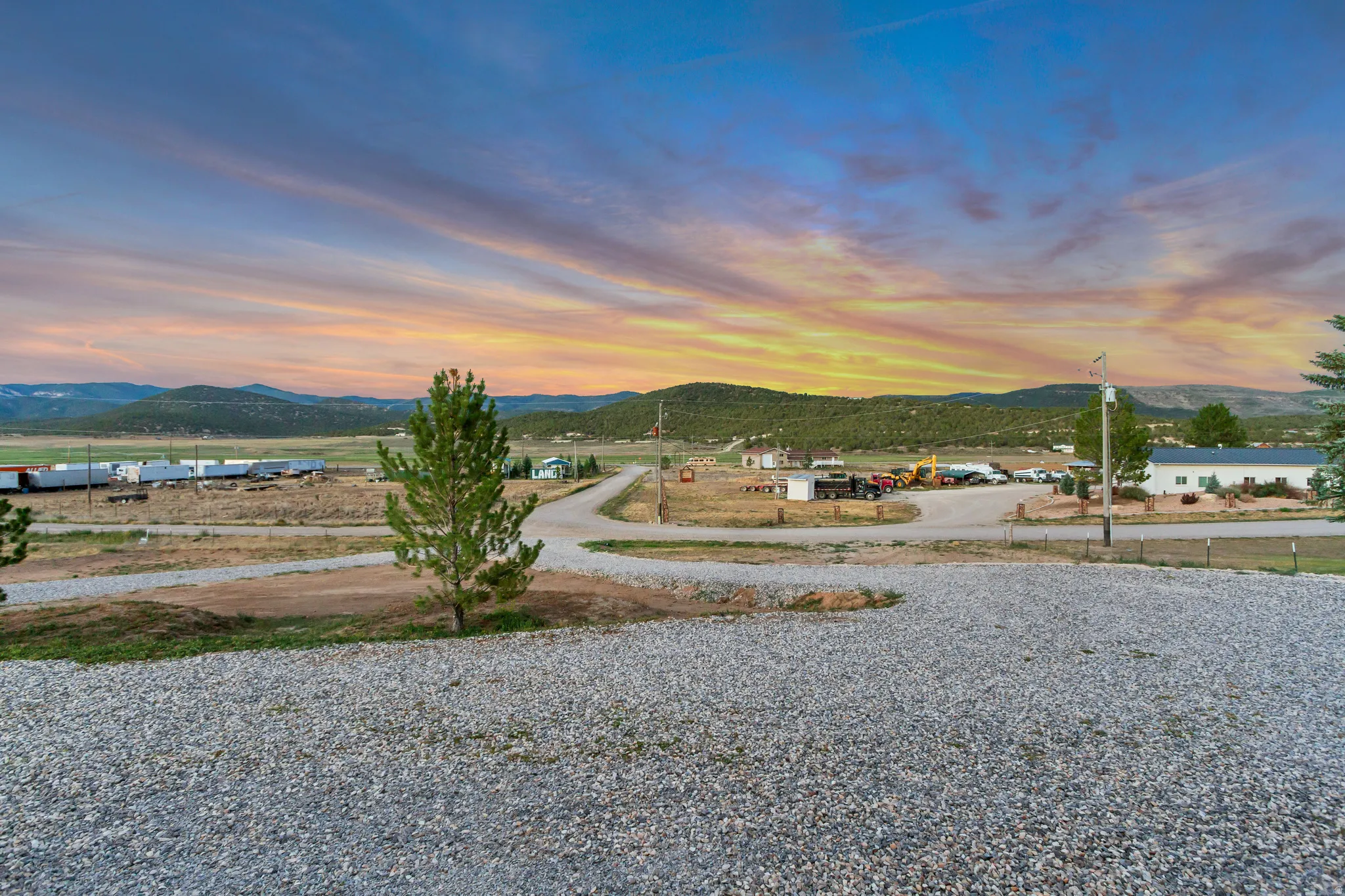 Expansive gravel lot with a young pine tree