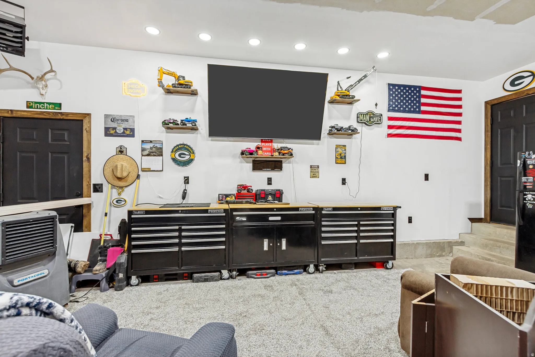 Finished interior space featuring recessed lighting, a mounted flat-screen television, and multiple black storage cabinets with wood-finish countertops