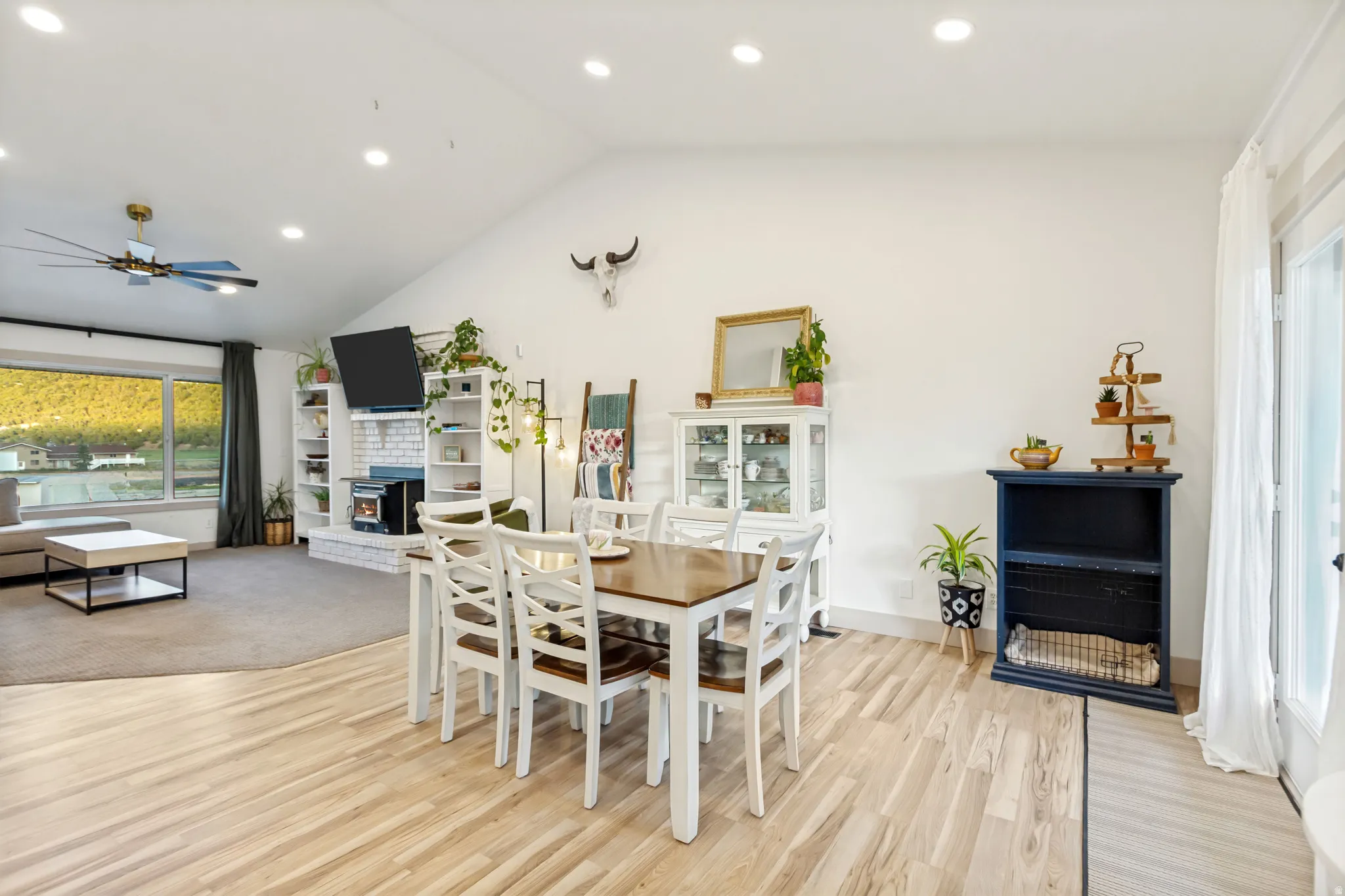 Spacious dining area with light wood-finish flooring, recessed lighting, and an adjacent living area