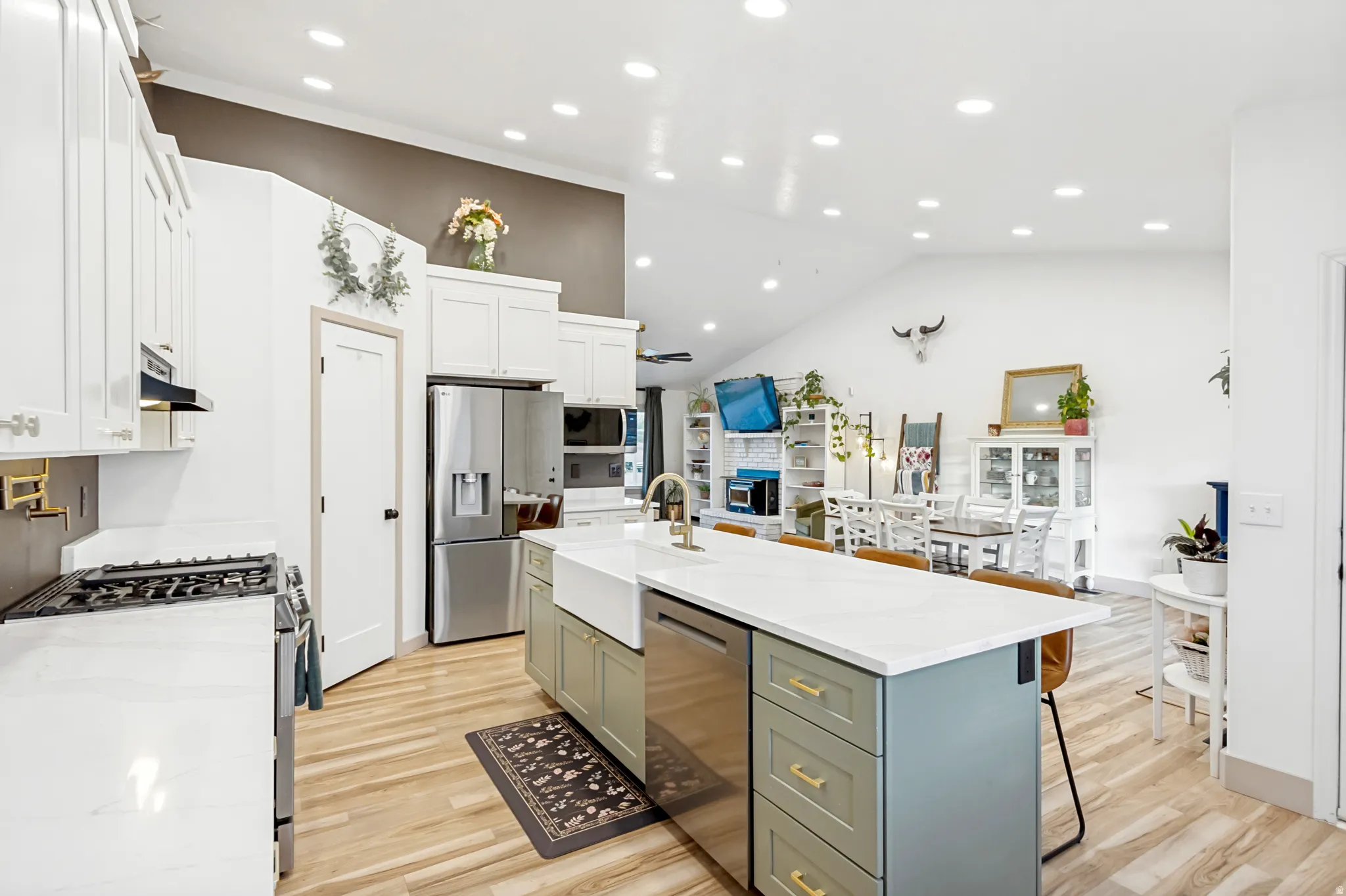 Modern kitchen featuring a large center island with a farmhouse sink, stainless steel appliances, and wood-finish flooring