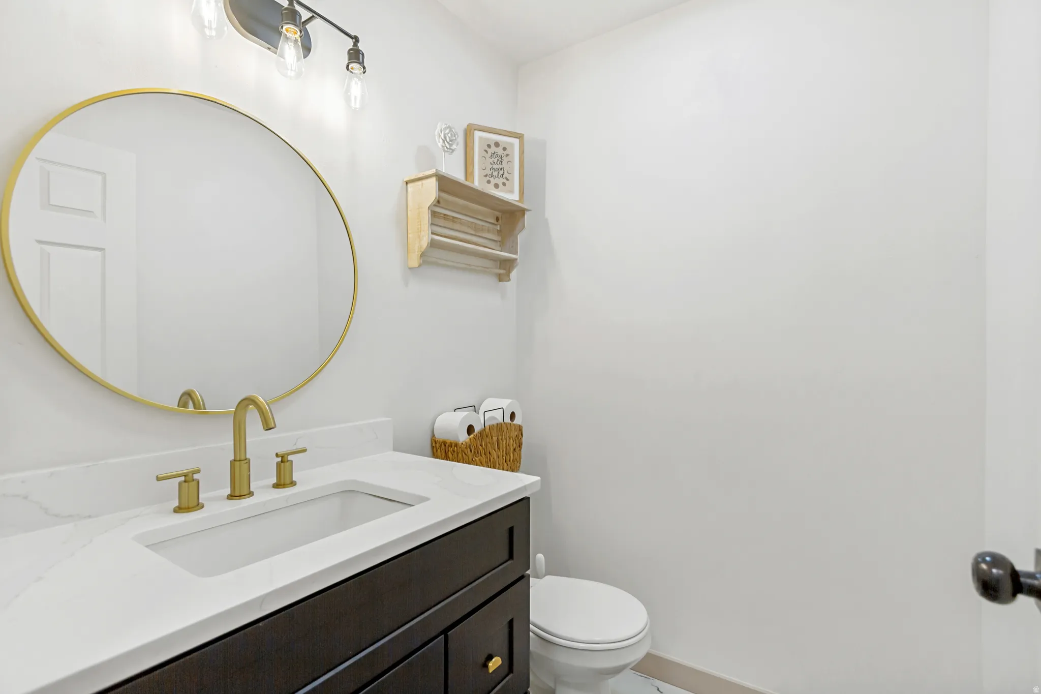 Contemporary vanity with a rectangular undermount sink, white countertop, and gold-finish faucet