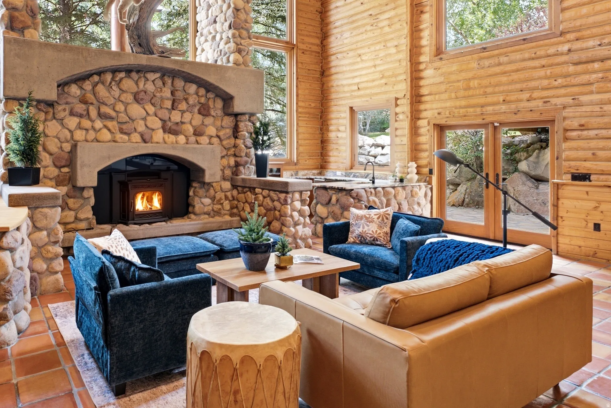 Expansive living space featuring a stone fireplace with an insert, log-paneled walls, and terracotta-style flooring