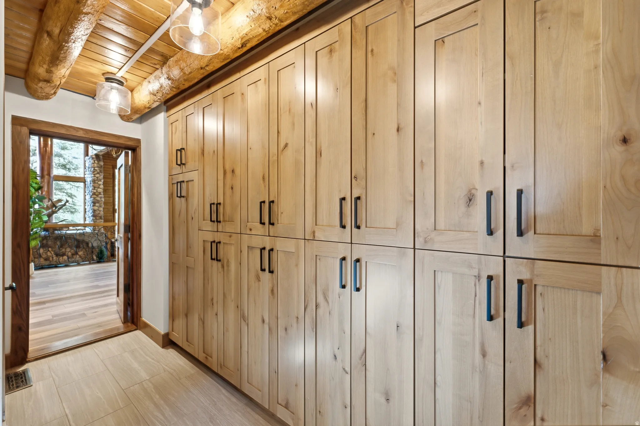 Custom wood cabinetry with black hardware, wood-finish flooring, exposed wood beams, and recessed lighting