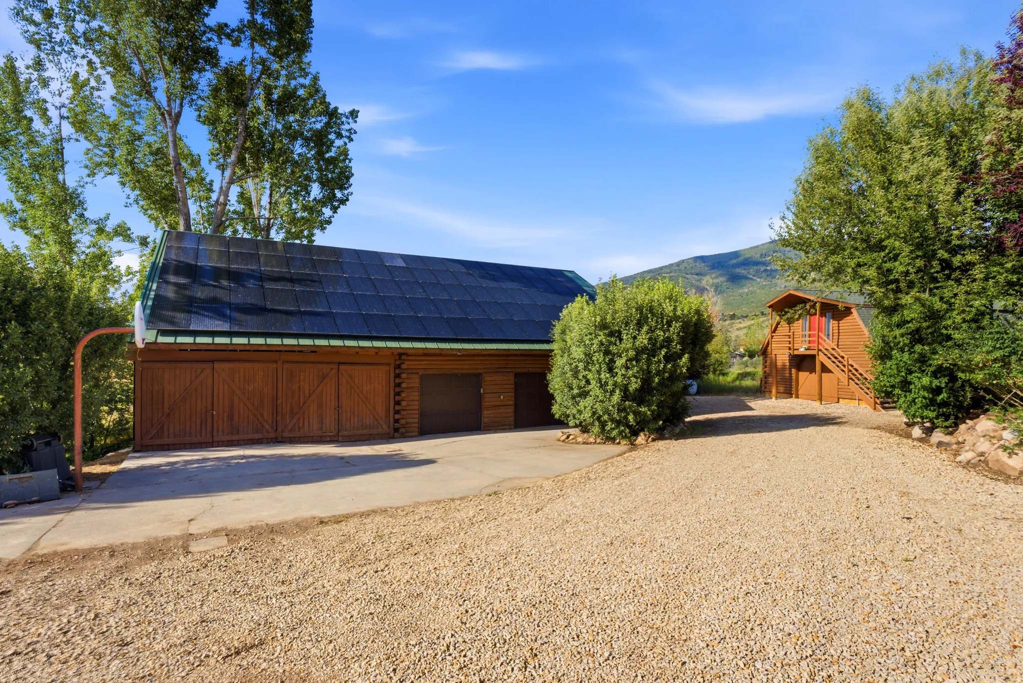 Expansive gravel drive with concrete approach leading to a multi-bay garage structure
