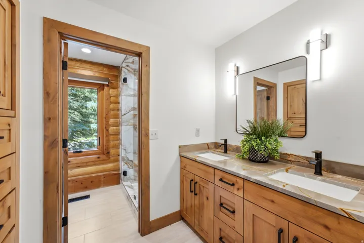 Dual vanity with custom wood cabinetry, stone countertops, and rectangular sinks