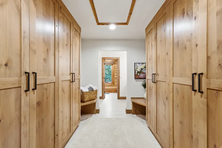Hallway featuring extensive built-in wooden cabinetry with black hardware, recessed lighting, and a tray ceiling with wood trim