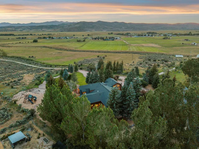 Mountain backdrop with expansive green fields and distant structures