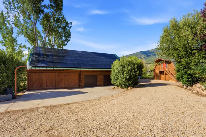 Expansive gravel drive with concrete approach leading to a multi-bay garage structure