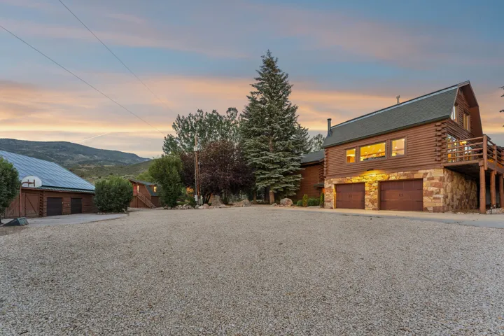 Log-sided residence featuring a multi-story design with stone accents and a two-car garage