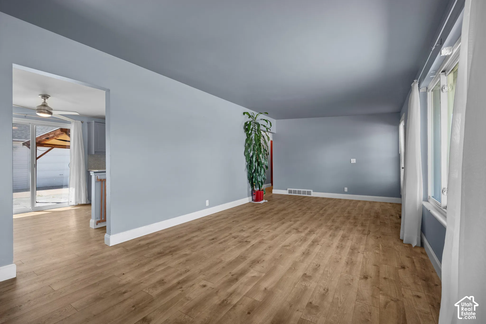 Living area featuring wood-finish flooring, neutral wall tones, large window, and sliding glass door