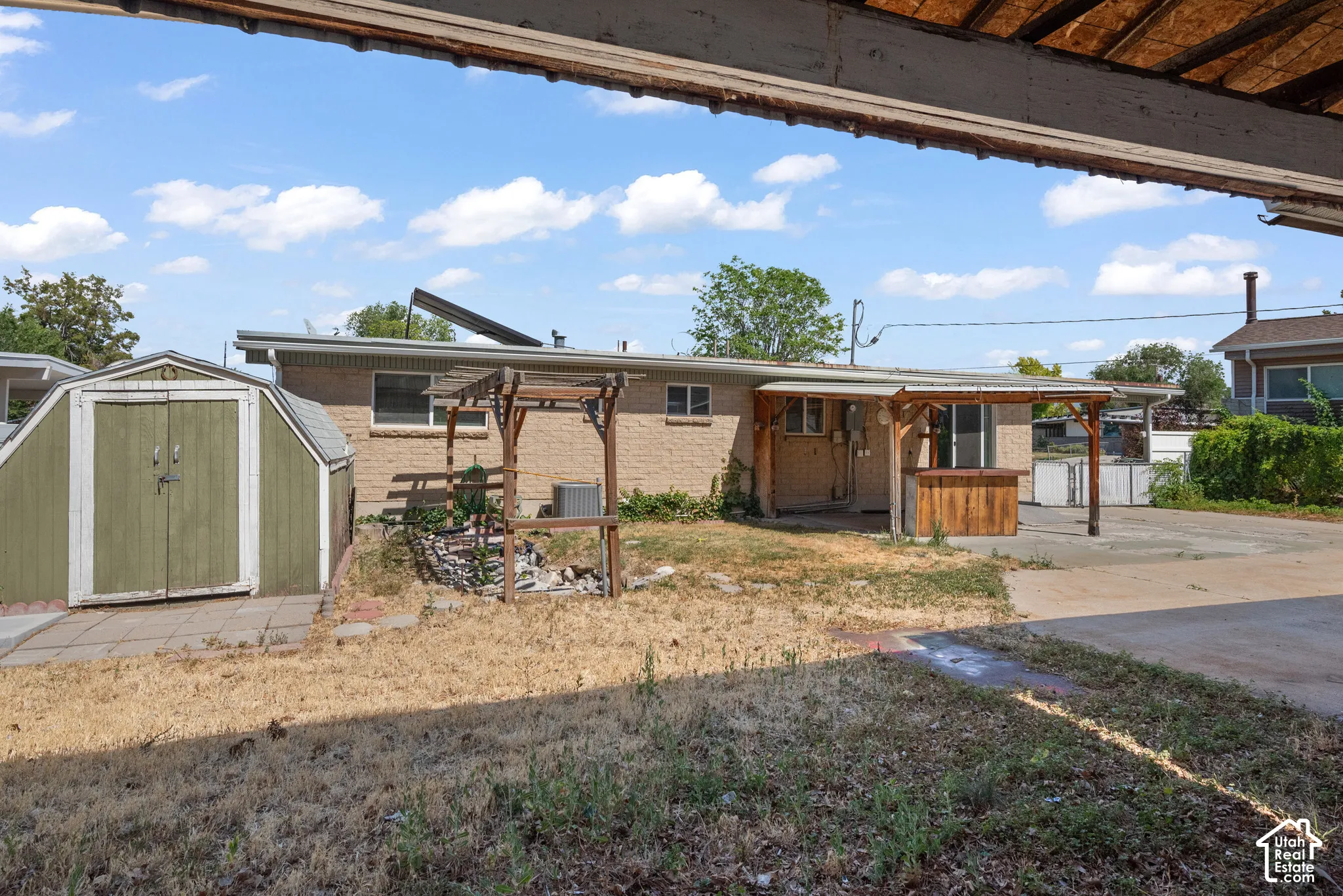 Exterior featuring brick siding, a detached storage shed, a wooden pergola, and a covered concrete patio