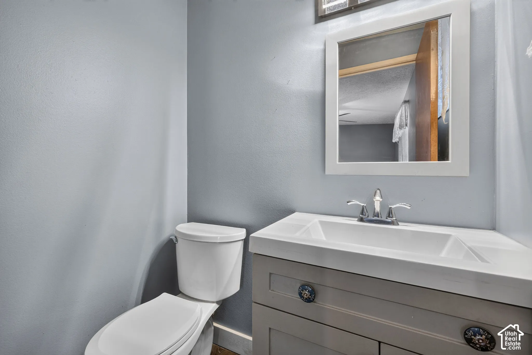 Vanity featuring a rectangular basin, neutral cabinetry, and decorative hardware, paired with a white-framed wall mirror and chrome dual-handle faucet