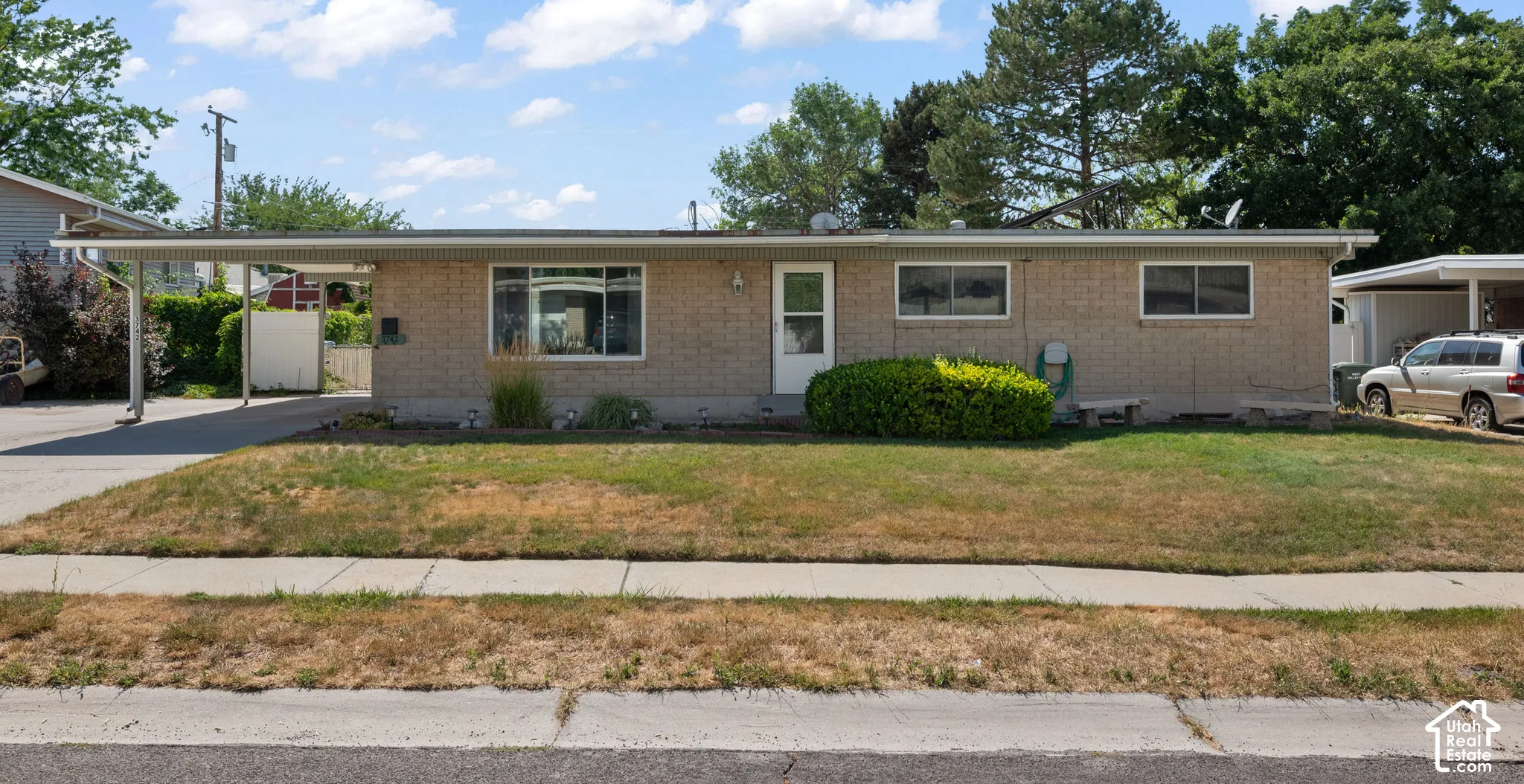 Single-story brick exterior featuring an attached carport and a concrete driveway