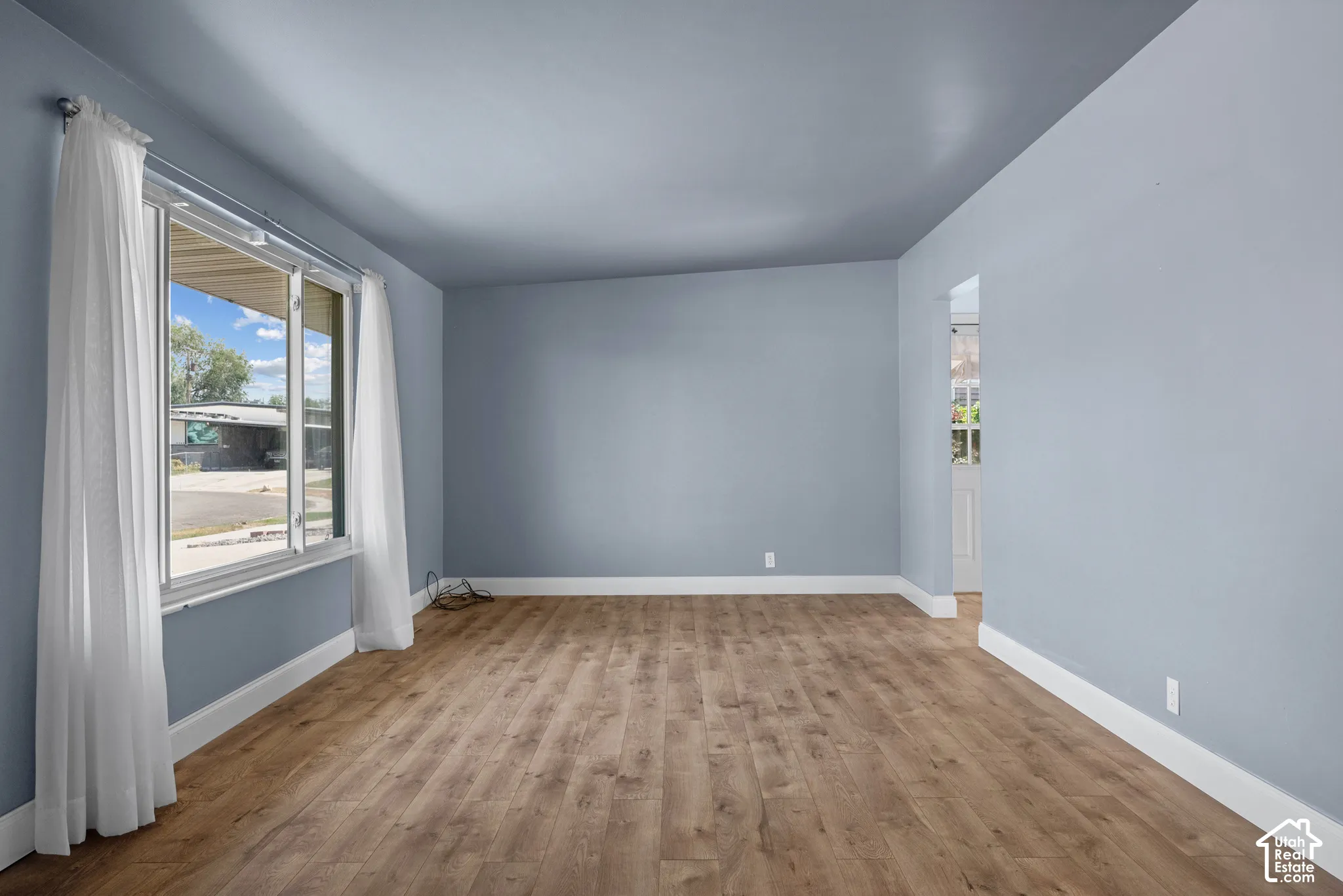 Interior room featuring wood-finish flooring, a large picture window, and neutral-toned wall paint