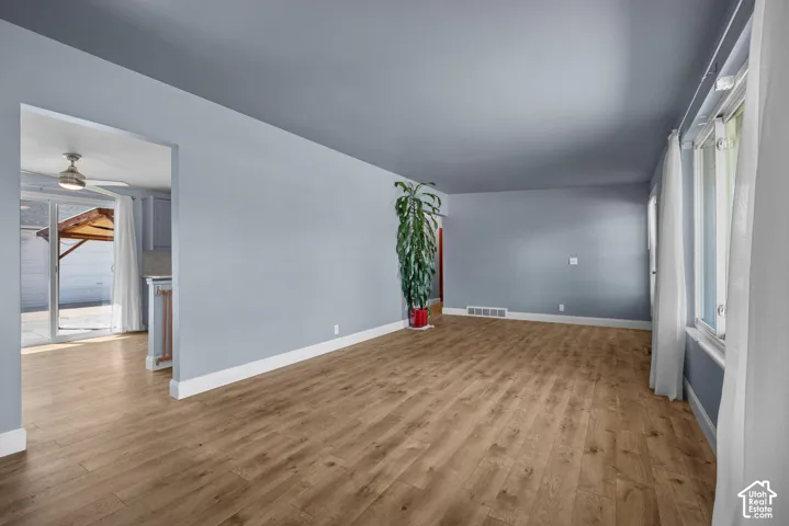 Living area featuring wood-finish flooring, neutral wall tones, large window, and sliding glass door