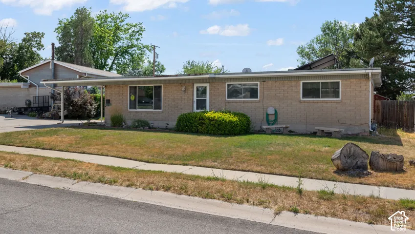 Single-story brick exterior featuring a metal-roofed carport, solar panels, and horizontal rectangular windows
