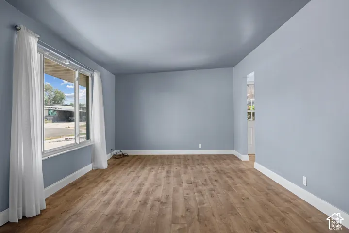 Interior room featuring wood-finish flooring, a large picture window, and neutral-toned wall paint