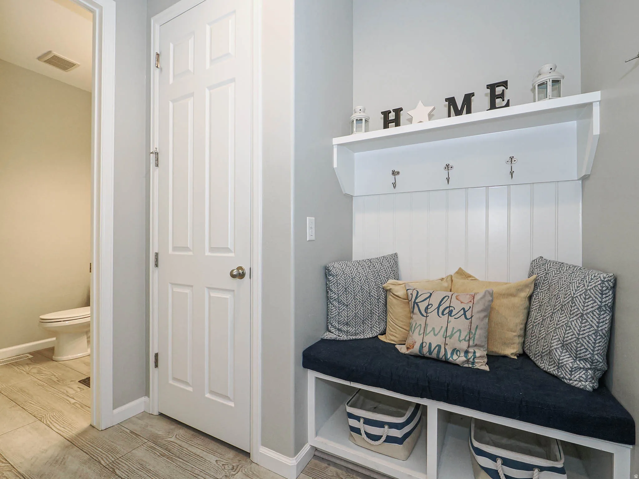 Built-in mudroom bench featuring beadboard paneling, integrated storage cubbies, and overhead shelving with coat hooks