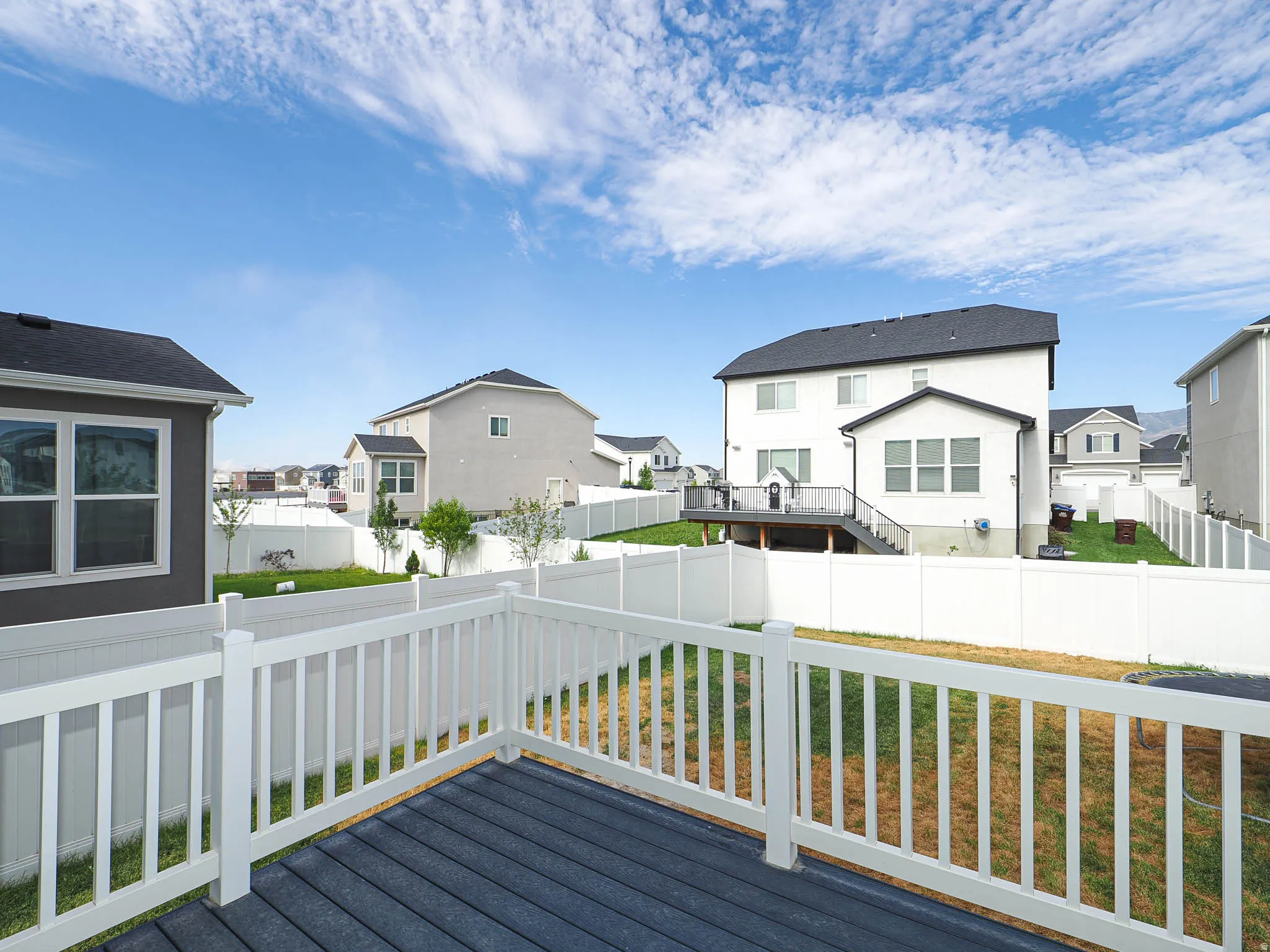 Deck with composite decking and white railing overlooking a fenced backyard