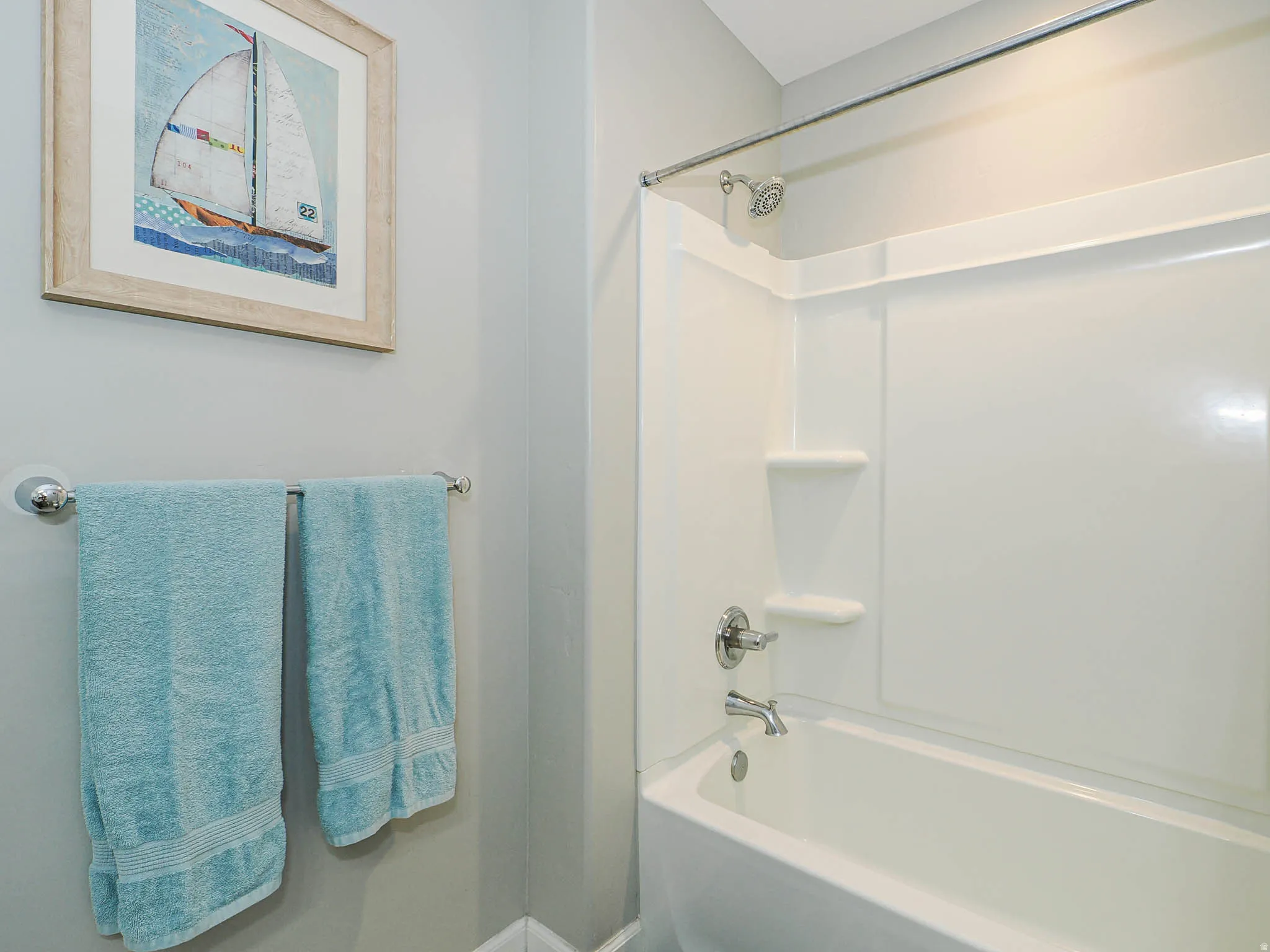 Bathtub with an integrated shower surround featuring a chrome showerhead and faucet
