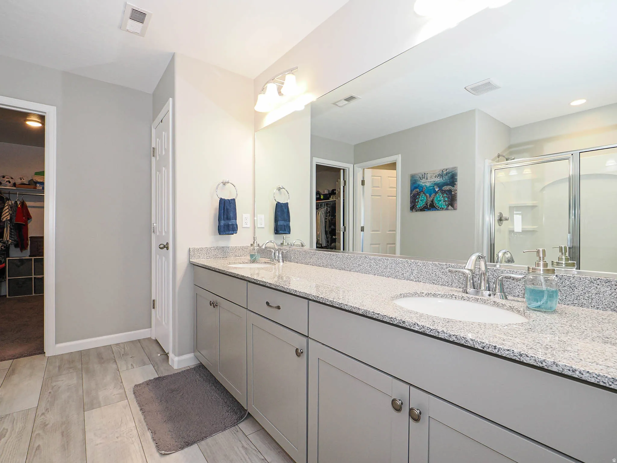 Double vanity with light gray cabinetry, built-in sinks, and speckled light countertops