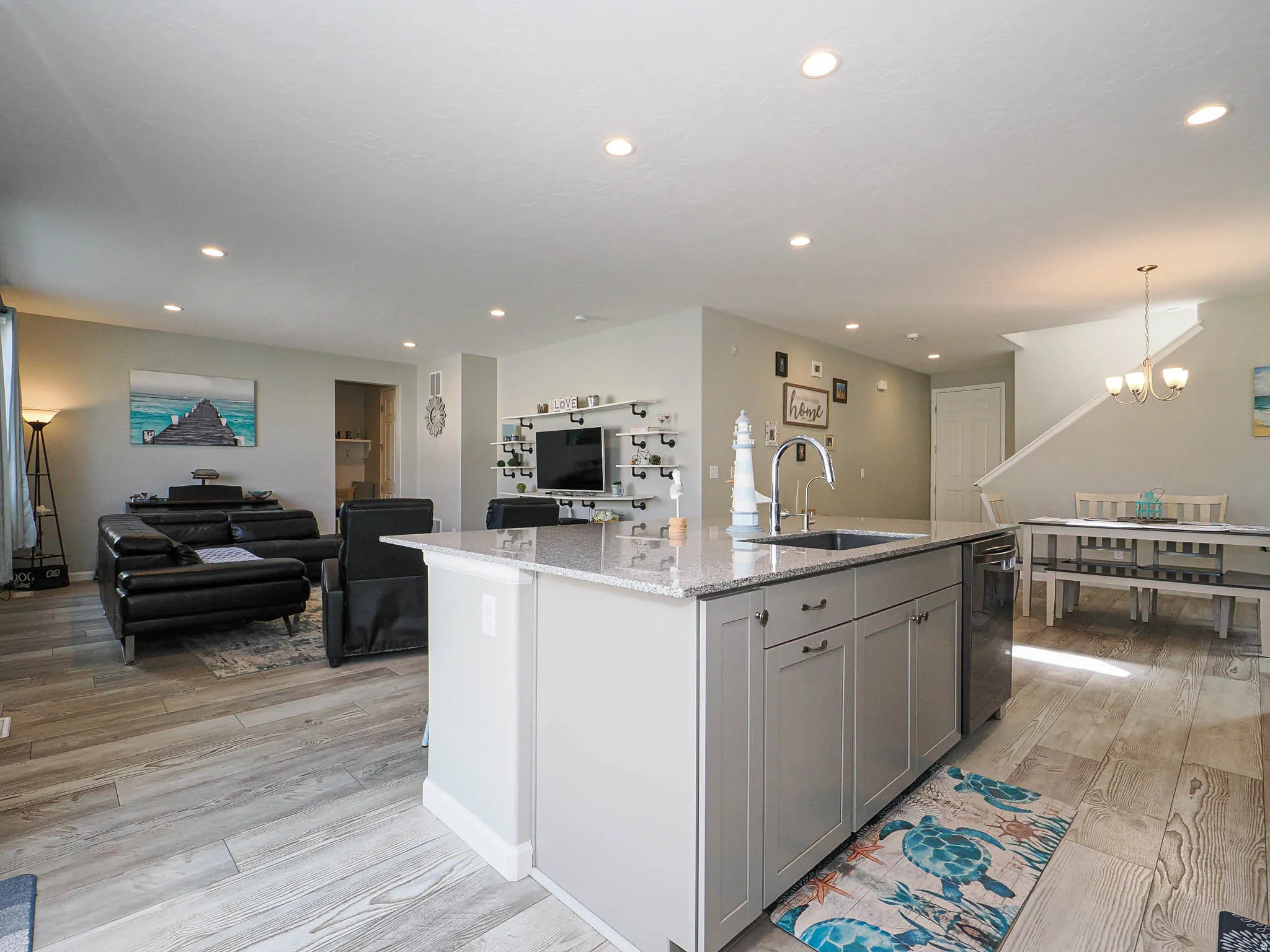 Central kitchen island featuring a granite-style countertop, undermount sink, and integrated dishwasher