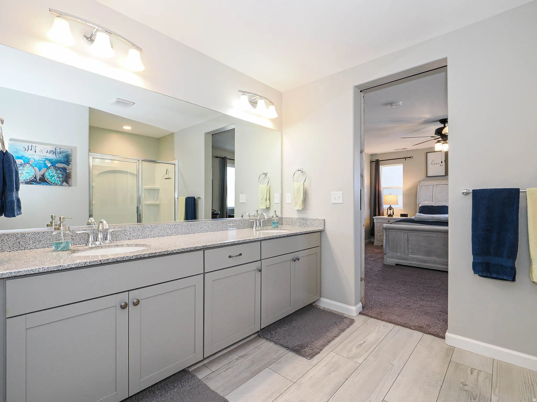 Bathroom featuring a dual vanity with granite-finish countertop, light gray cabinetry, and undermount sinks
