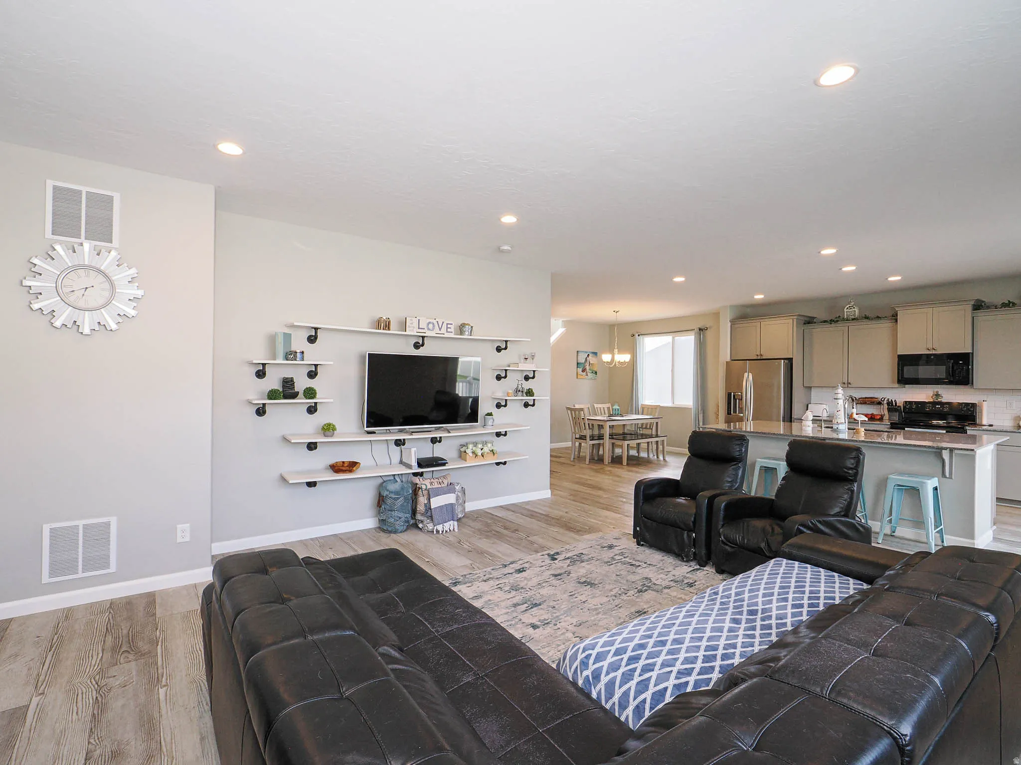 Open-concept living area featuring wood-finish flooring, recessed lighting, and a built-in shelving unit