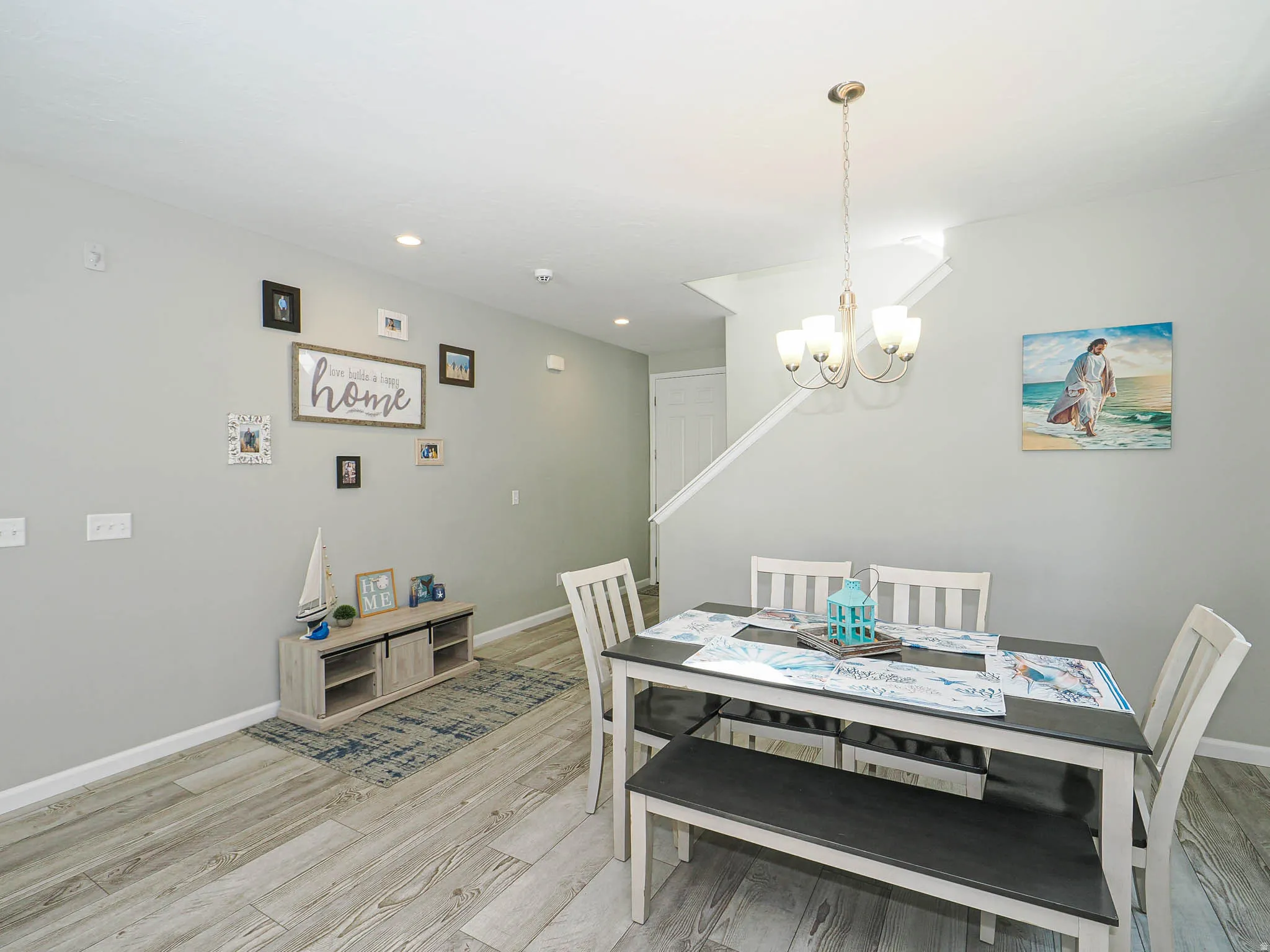 Dining area featuring wood-finish flooring, light gray wall tones, and a staircase with white risers