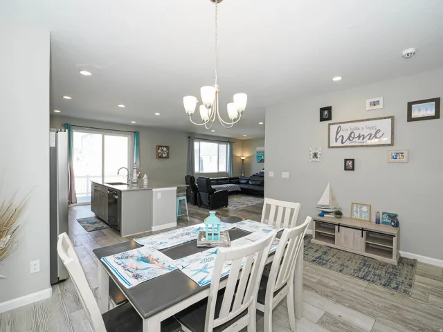 Open-concept dining area featuring wood-finish flooring, recessed lighting, a decorative chandelier, and a built-in kitchen island with integrated sink