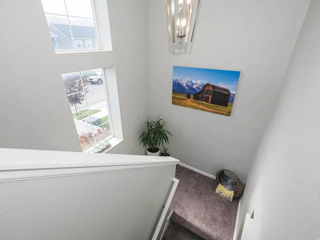 Two-story foyer featuring natural light from multiple windows, a decorative contemporary light fixture, and a neutral color palette