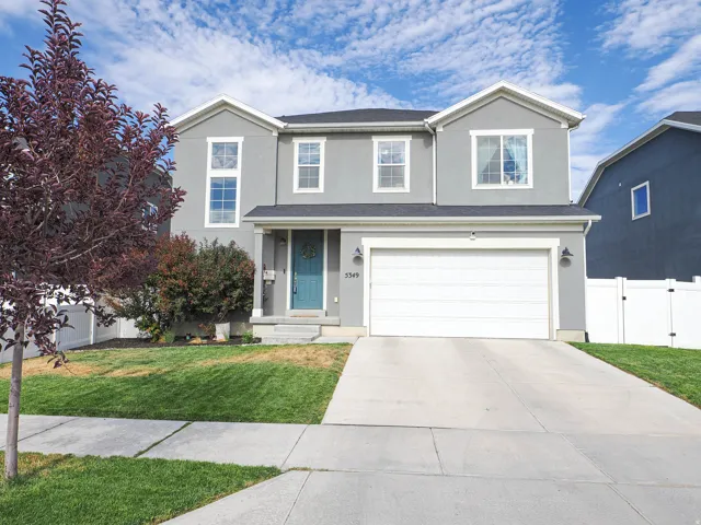 Two-story stucco residence featuring a two-car garage, a bright teal entry door, and white frame windows
