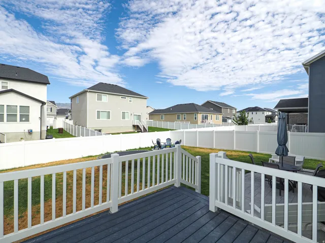 Expansive backyard featuring a full vinyl privacy fence, a multi-level deck with composite decking, white railing, and a ground-level patio
