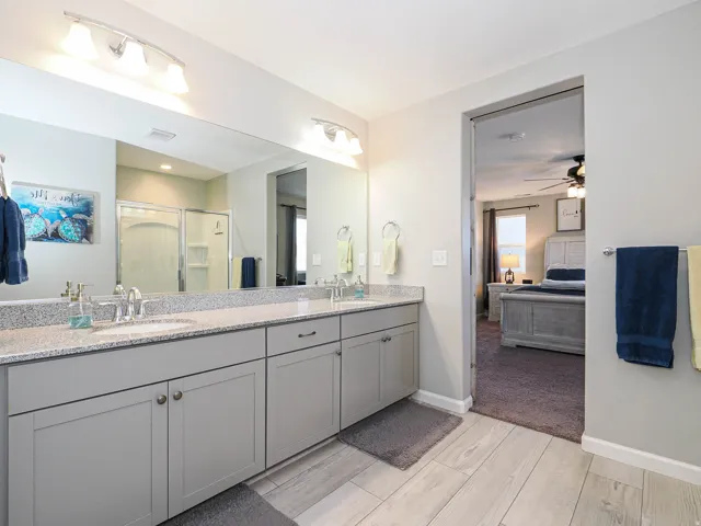 Bathroom featuring a dual vanity with granite-finish countertop, light gray cabinetry, and undermount sinks