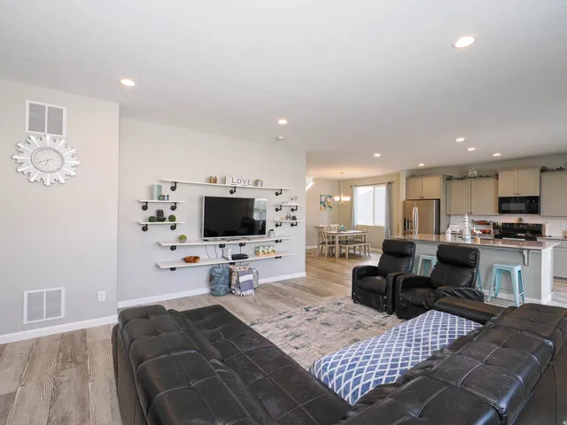 Open-concept living area featuring wood-finish flooring, recessed lighting, and a built-in shelving unit