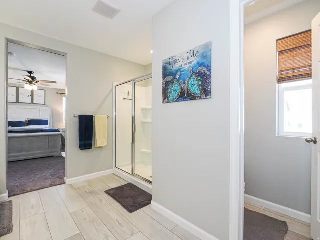 Light-toned wood-finish flooring extending into the shower area