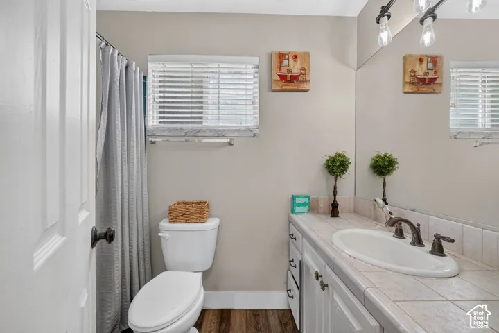 Bathroom featuring a white vanity with an integrated sink, tile countertop, and track lighting fixture