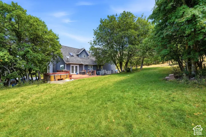 Expansive green lawn with mature trees and a multi-level rear deck
