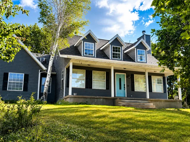 Charming two-story exterior featuring dark gray siding, a white columned porch, and a bright blue front door