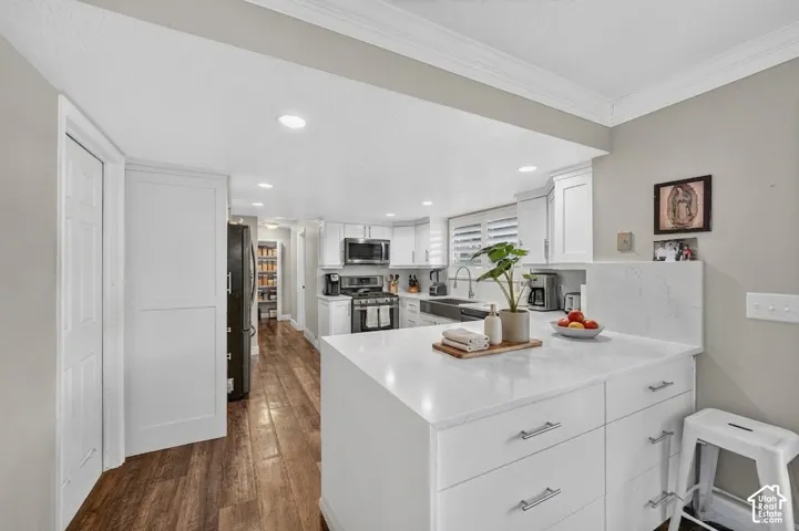 Spacious kitchen featuring an expansive central island with quartz countertops, white shaker cabinetry, recessed lighting, and wood-finish flooring