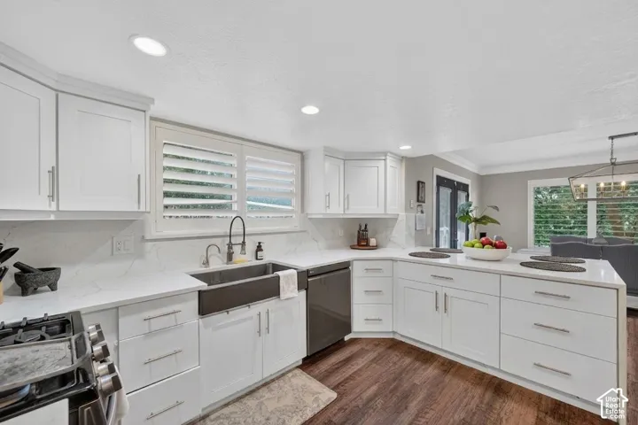 Kitchen featuring white shaker cabinetry, white countertops, wood-finish flooring, a farmhouse sink with a gooseneck faucet, and stainless steel appliances