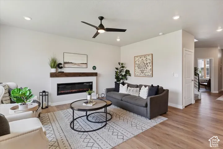 Living space featuring a built-in fireplace with a wood mantle, a ceiling fan, recessed lighting, and wood-finish flooring