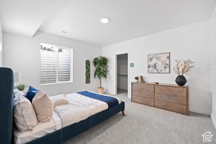 Carpeted  basement bedroom featuring a large window, recessed lighting, and a built-in closet with shelving