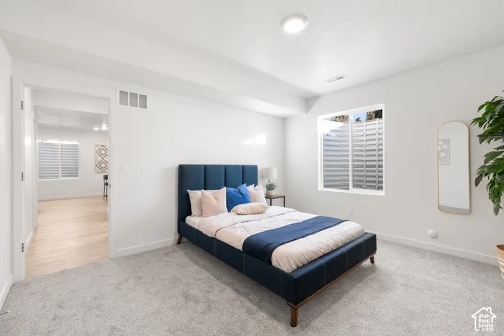Carpeted basement bedroom with a window featuring horizontal blinds