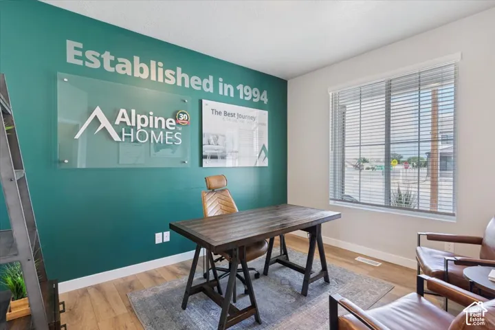 Main floor office featuring a vibrant accent wall, wood-finish flooring, and a large window